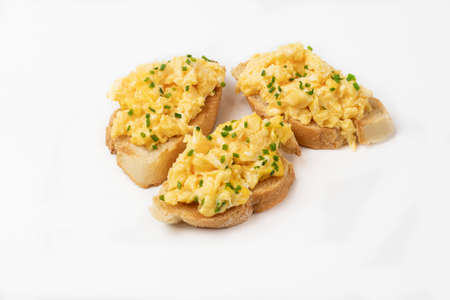 Scrambled eggs served on bread toast on white backgroundの写真素材