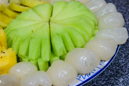 A fruit plateRambutan, melon, kiwi, golden, pineappleの写真素材