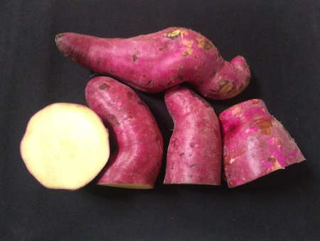 sweet pink potatoes on the black background close up photoの写真素材