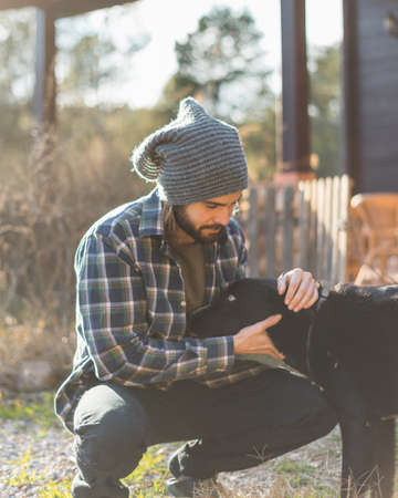 Portrait of a bearded man with his old dog and a beautiful sunset on the mountainの写真素材