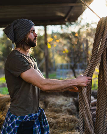 Portrait of young bearded man taking the rope with beautiful sunlightの写真素材