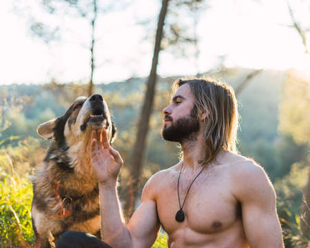 Portrait of a bearded man with his old dog and a beautiful sunset on the mountainの写真素材