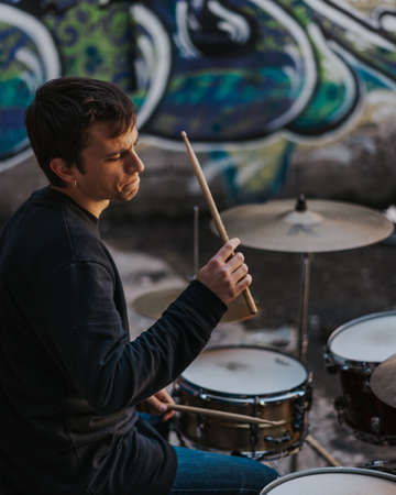 Young man playing drums in an underground environmentの写真素材