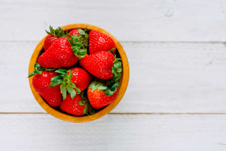Organic strawberries on a bowl on a white wooden table much colorfulの写真素材