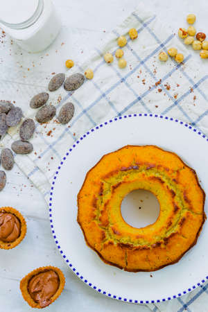 Organic corn cake with hazelnuts, coconut milk and chocolate candies in a square plate on a wooden tableの写真素材