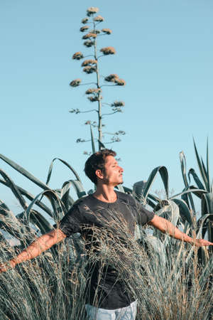 Young man posing in a natural landscape looking at the sun with cactus on the backgroundの写真素材