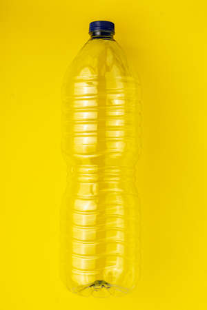 Empty plastic bottle of water on a yellow background. Concept of collecting garbage to the yellow containerの写真素材