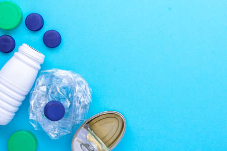 Recycling garbage. White plastic bottle, green cap, blue caps, can of sardines grouped on the left side diagonal on a blue background.の写真素材