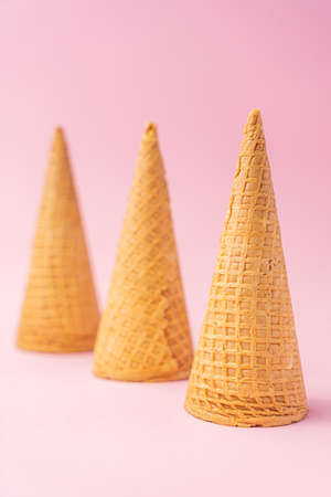 Three upside down wheat flour ice cream cones diagonally towards the bottom on a pink background. Summer concept.の写真素材