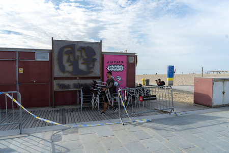 BARCELONA; SPAIN - MAY 25th 2020: First day of the phase 1 of the coronavirus disease (COVID-19) in Barcelona, beach bar worker setting up the terrace to receive his first customersのeditorial素材