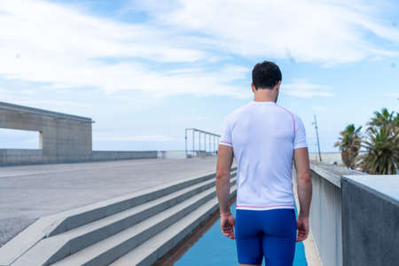 Young runner man in blue pants and white t-shirt running in the sun on a blue track. Motivation concept, careerの写真素材
