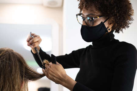 beautiful young hairdresser cutting hair to handsome man in beauty salonの写真素材