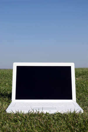 Royalty Free Stock Image of a photograph of a laptop on grass against a clear blue sky providing copy space above in a conceptual mannerの写真素材