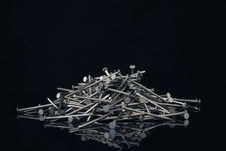 Royalty free stock image close up of a pile of nails against black providing copyspace above and on a reflective surfaceの写真素材