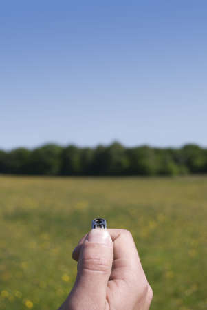 Royalty free stock image of a close up of male hand holding a lighter with woodland in backroung in a conceptual manner suggesting intent to do damage to the treesの写真素材