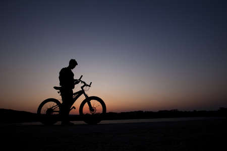 a cyclist listen music on city background at the sunsetの写真素材