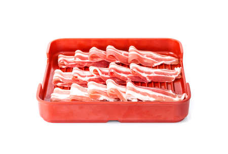 bacon sliced in red ceramic tray isolated on white backgroundの写真素材