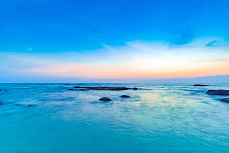 Long exposure shot of calmness sea and the rock in beautiful sunset skyの写真素材