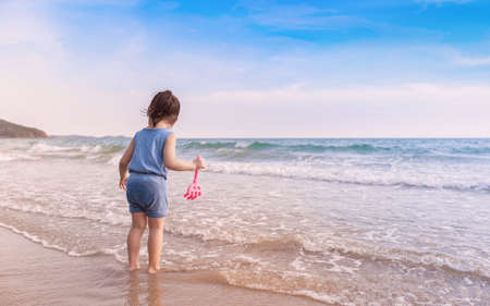 little asian adorable girl 2-3 years plays joyfully on the beach in sunsetの写真素材