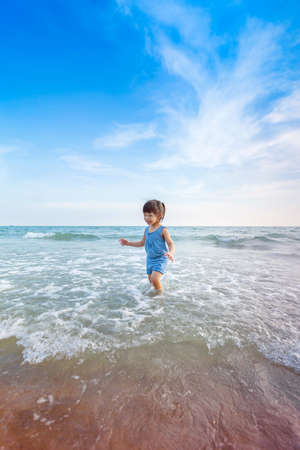 little asian adorable girl 2-3 years plays joyfully on the beach in sunsetの写真素材