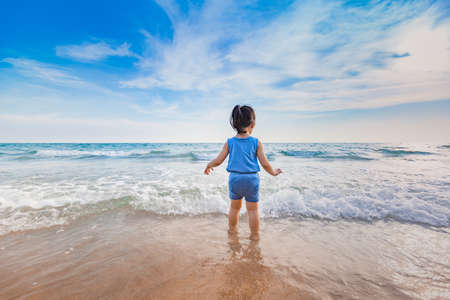 little asian adorable girl 2-3 years plays joyfully on the beach in sunsetの写真素材