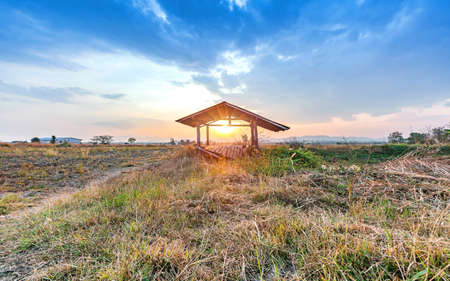 beautiful sunset at countryside agriculture dry field with the hut in harvest seasonの写真素材