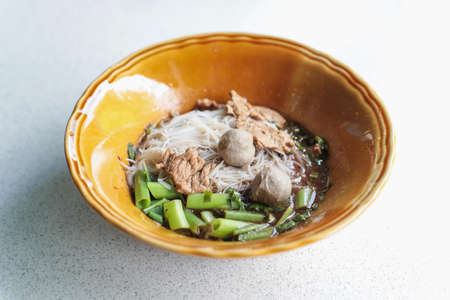 Thai classic noodles soup, thin rice noodles with meat balls, beef and morning glory vegetable in classic brown bolwの写真素材