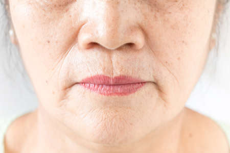 wrinkled and lines of old asian woman skin texture in closeup selective focusの写真素材
