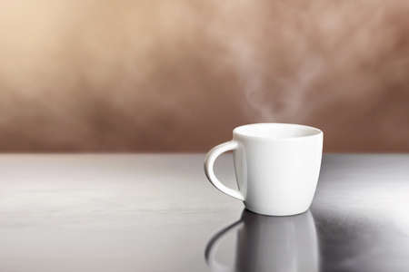 white ceramic hot coffee cup on wooden table with steamの写真素材