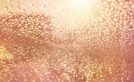 Droplets of rain on car wind shield reflection with glow sunlight in morning rainydayの写真素材