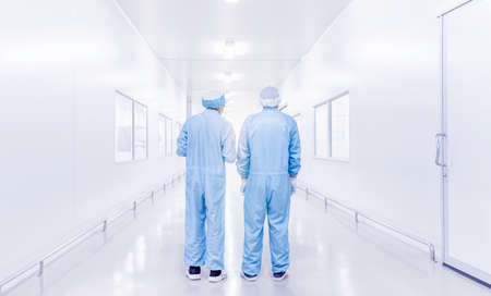 modern interior of laboratory or factory with back view of two science workers in coverall uniform, science development concept backgroundの写真素材