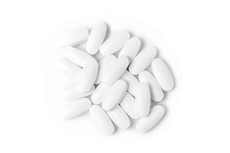 heap of white medicine tablets in selective focus on white backgroundの写真素材