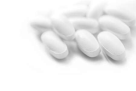 heap of white medicine tablets in selective focus on white background