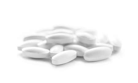 heap of white medicine tablets in selective focus on white background