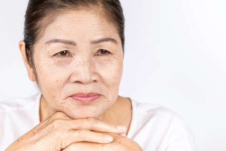 elderly asian woman portrait 60-70 years old with black hair and hazel eyes looking serious thinking isolated on white background with copy spaceの写真素材