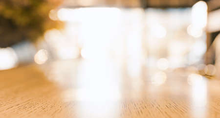 Wood table top with blurred brighten sunshine in coffee shop or cafe, restaurant background For...