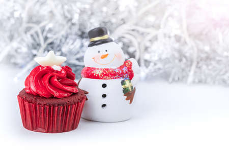 Merry Christmas and Happy New Year with red cupcake and snowman statuette and snowflake ribbon backgroundの写真素材