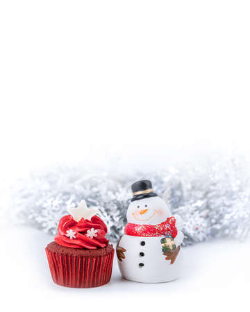 Merry Christmas and Happy New Year with red cupcake and snowman statuette and snowflake ribbon backgroundの写真素材