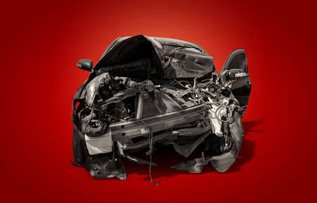 carcass of crashed black car in front side isolated on crimson red burn background with clipping path, Car insurance and accident conceptの写真素材