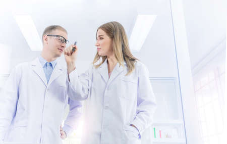 Scientists brainstorming for some confidential and write a plan on transparent board in laboratory,...