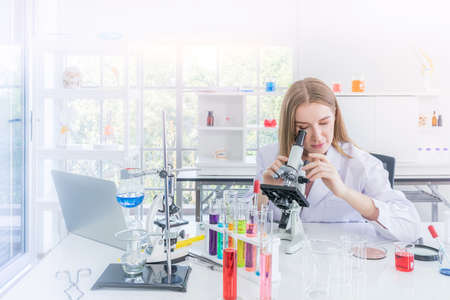 pretty scientist looking through a microscope in chemical laboratory, Science and healthy or medical conceptの写真素材
