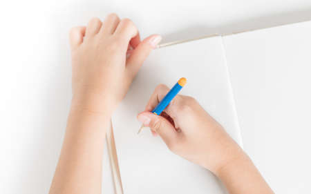 Hands of little kid hold the pencil and drawing on the blank book for creativity conceptの写真素材