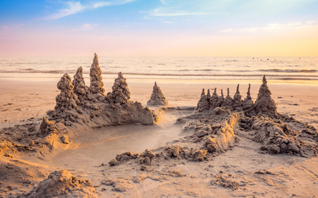 Sandcastle on the beach with warming light and beautiful sunset sky in summer vacation timeの写真素材