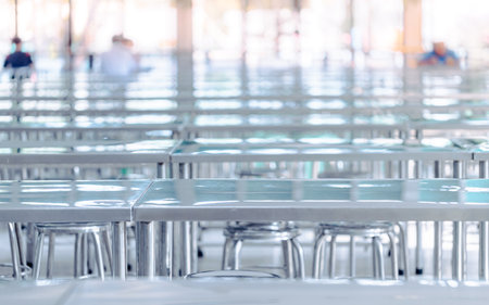 Modern interior of cafeteria or canteen with stainless steel chairs and tables, eating room in selective focusの写真素材