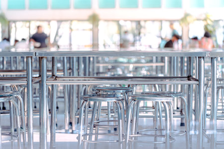 Modern interior of cafeteria or canteen with stainless steel chairs and tables, eating room in selective focusの写真素材