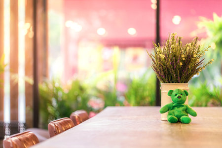 Green teddy bear on the top of wooden table in coffee shop at the morning, cafe or coffee shop backgroundの写真素材