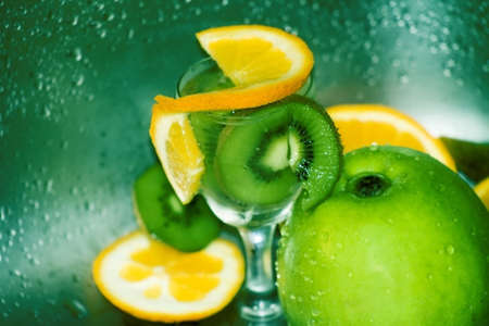 Slices of oranges and kiwi and an apple, in fresh waterの写真素材