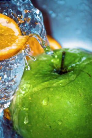 Close-up on water falling above oranges and an appleの写真素材