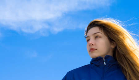 Beautiful blond girl facing the future, with sky as backgroundの写真素材