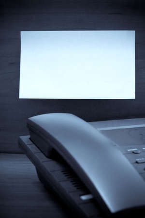 Close-up view of office telephone and blank post-it note in backgroundの写真素材